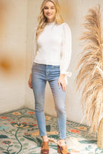 Load image into Gallery viewer, Woman wearing a white blouse and blue jeans standing in a room with decorative elements.