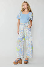 Load image into Gallery viewer, A stunning model exudes elegance in a captivating blue top and wide-leg pants adorned with a retro-inspired floral print. The pants, effortlessly worn with a self-tie belt, evoke dreams of a sun-kissed getaway.