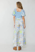 Load image into Gallery viewer, A captivating vision, the model effortlessly showcases a fashionable blue top and wide-leg pants in a delightful floral print.