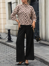 Load image into Gallery viewer, Woman wearing a leopard print top and black pants standing on a street.