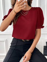 Load image into Gallery viewer, Person wearing a red blouse with puff sleeves and black pants against a white wall.