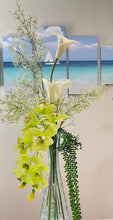 Load image into Gallery viewer, A beautiful vase with vibrant artificial Cymbidium orchids surrounded by real touch flowers and a serene ocean picture.