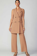 Load image into Gallery viewer, A stylish model in a tan dress with wide leg pants, exuding elegance and style in the Sleeveless Double Breasted Longline Vest Dress from Current Air.