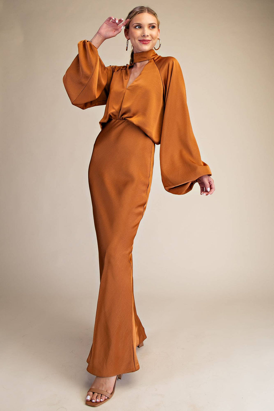A stylish copper-toned outfit with a high collar and flowing long sleeves, fitted. Key hole detail adds a touch of fun femininity.  