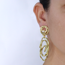 Load image into Gallery viewer, Chic clip-on earrings with a polished swirling drop, 1.75&quot; long, crafted from pewter and available in gold, silver, and rose gold.
