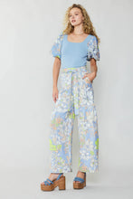 Load image into Gallery viewer, A stunning model exudes elegance in a captivating blue top and wide-leg pants adorned with a retro-inspired floral print. The pants, effortlessly worn with a self-tie belt, evoke dreams of a sun-kissed getaway.
