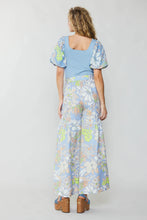 Load image into Gallery viewer, A captivating vision, the model effortlessly showcases a fashionable blue top and wide-leg pants in a delightful floral print.
