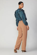 Load image into Gallery viewer, A stylish model donning a blue blouse and wide-leg trousers. The trousers feature pleats, a partially elasticized waistband, and front/back pockets.
