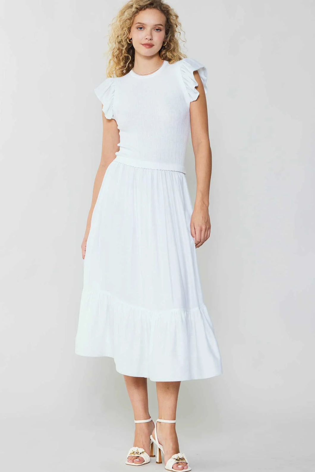 Short-sleeved white midi dress with ruffled hem. Sweater bodice, crew neckline, dropped waist, mid-length skirt. 