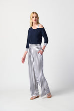 Load image into Gallery viewer, Chic woman donning blue top and striped pants, epitomizing timeless fashion with a touch of flair.

