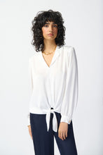 Load image into Gallery viewer, A woman wearing a white shirt and navy pants, with a tailored satin top featuring a notch collar, lapels, and centre-front ties. The puff sleeves&#39; cuffs are adorned with gold buttons, while sleek yokes at the shoulders add structure and style.
