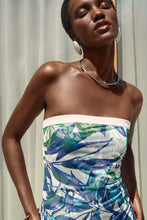 Load image into Gallery viewer, Gracefully posing, a woman wears a blue and green dress in the form of a silky knit strapless jumpsuit. Vibrant tropical print enhances its irresistible appeal.
