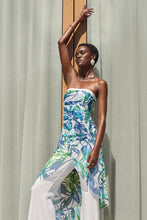 Load image into Gallery viewer, Silky knit strapless jumpsuit in blue and green, worn by a woman posing gracefully. Vibrant tropical print adds irresistible appeal.
