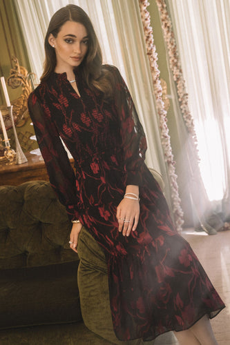 Smocked midi dress with flattering silhouette and sheer long sleeves. Black with red floral design.