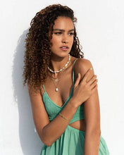 Load image into Gallery viewer, A woman with beautiful curly hair and dressed in green, adds sophistication to her look with a stunning baroque pearl pendant necklace.
