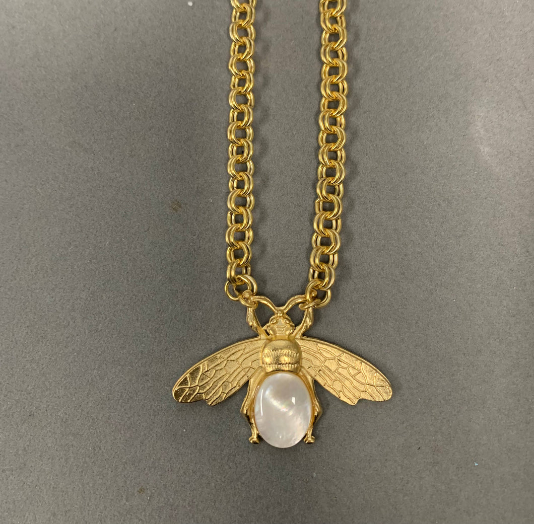 Gold bee-shaped necklace with a white stone accent.