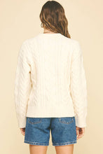 Load image into Gallery viewer, Person wearing a cream cable knit sweater and blue denim shorts on a beige background
