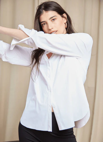 Woman in white shirt and black pants, showcasing the Connie Slim Button Down with a longer back hem and wrinkle-resistant Microfiber material.