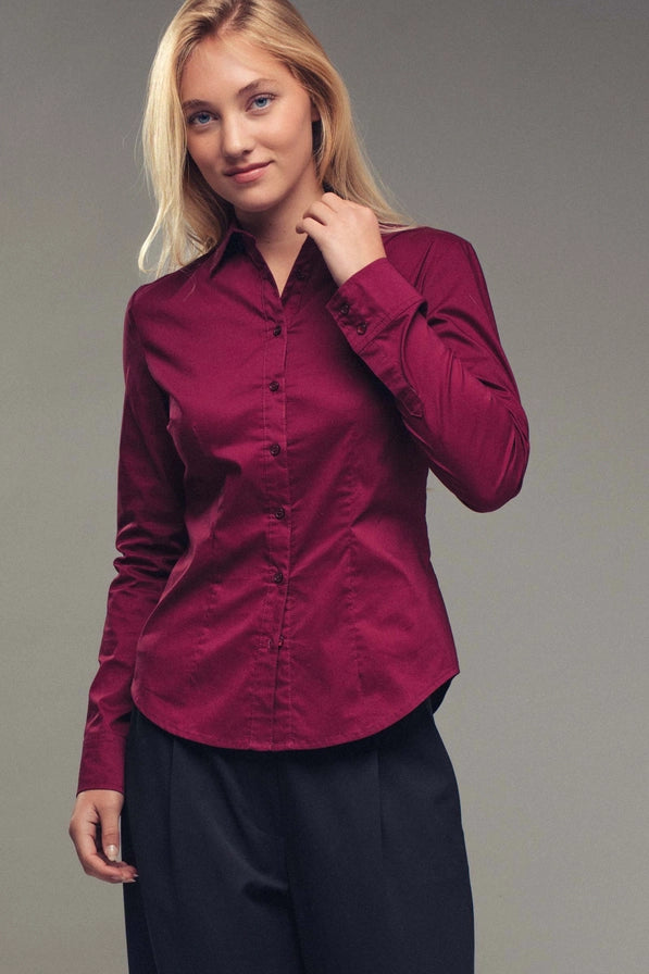 Woman wearing a burgundy shirt against a gray background