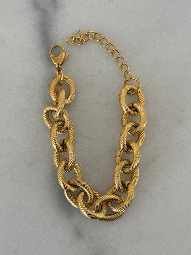 Gold chain bracelet on a light gray background