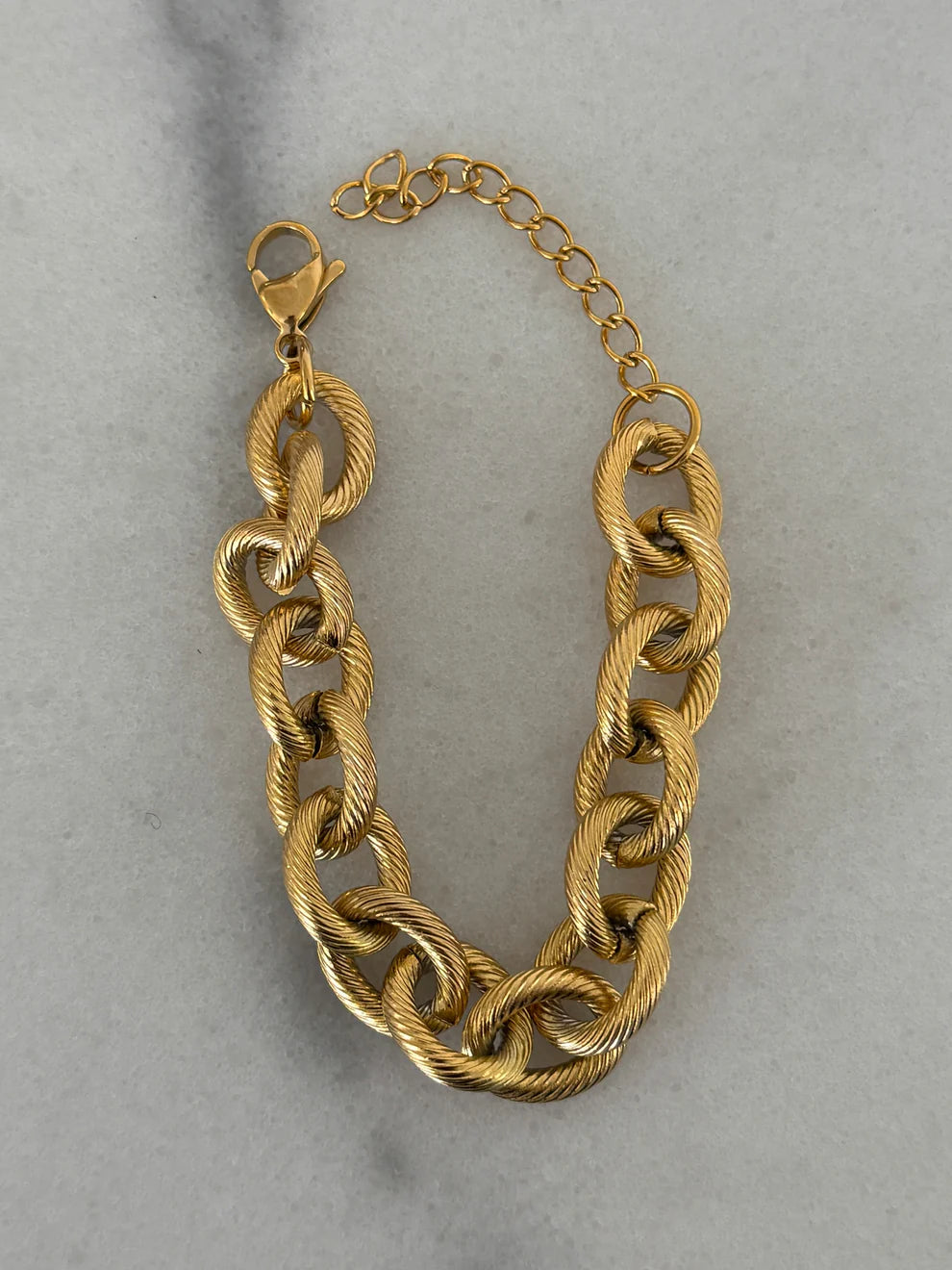 Gold chain bracelet on a light gray background