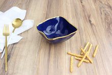 Load image into Gallery viewer, Square snack bowl in Sunset By The Sea. Versatile for snacking, dips, or toppings. Ideal for bar use. Crafted in blue glazed porcelain with gold-tone rims. Food safe, dishwasher safe, and oven safe to 500°. Easy to care for.
