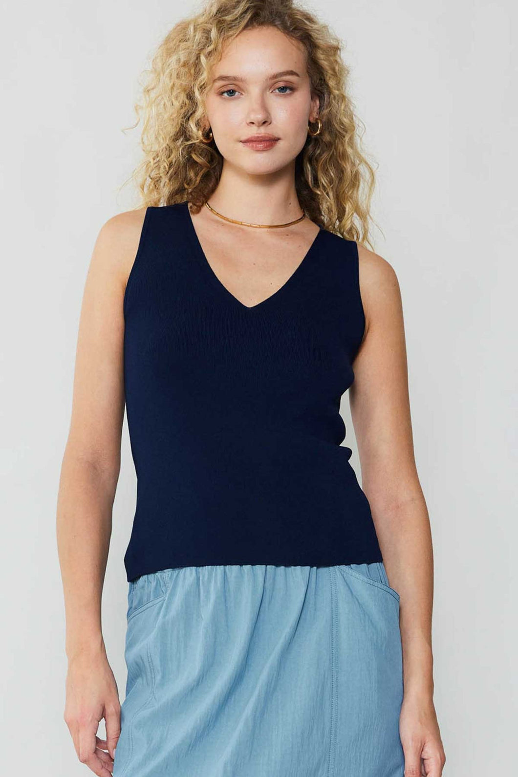 The model showcases sophistication in a navy blue skirt and a v-neck top, elevating any outfit with elegance