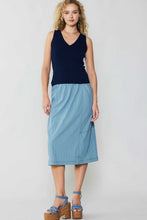 Load image into Gallery viewer, A stylish woman adorned in a chic ensemble, consisting of a blue skirt and a coordinating top, emanating class and elegance.
