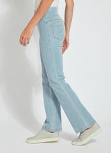 Load image into Gallery viewer, A woman wearing jeans made from stretchy Knit Denim. The jeans have studded back pockets and contrast-color top stitching.
