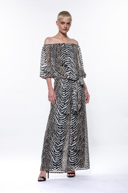 A zebra print outfit adorns a model, epitomizing glamour and trendiness. The Luna Top by Julian Chang enhances the ensemble with its off-the-shoulder neckline, loose sleeves, and effortlessly chic style.