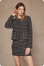 Load image into Gallery viewer, Woman wearing a black and white patterned outfit against a beige background
