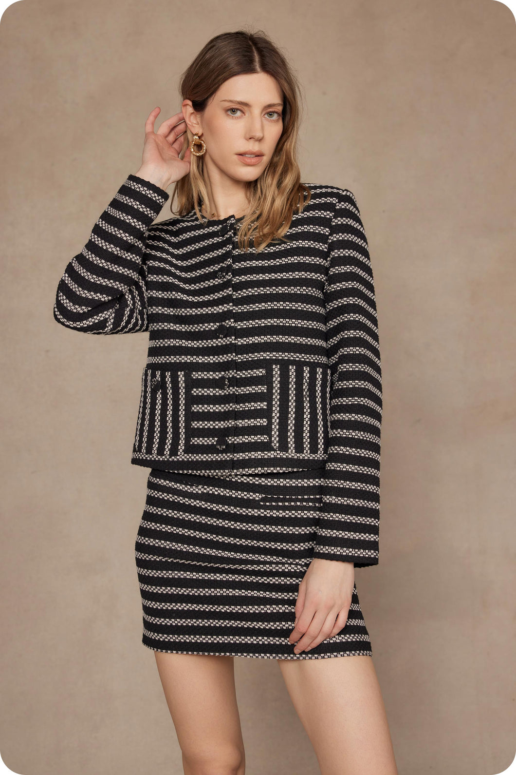 Woman wearing a black and white patterned outfit against a beige background