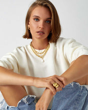 Load image into Gallery viewer, A woman wearing a white sweater and jeans. She accessorizes with a pearl and gold chain necklace featuring a genuine freshwater pearl on a chunky gold chain. 
