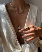 Load image into Gallery viewer, The woman is adorned in gold jewelry, including a magnificent baroque pearl necklace, while donning a white shirt.
