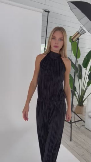 Black plisse Holly Jumpsuit by Julian Chang: Two-piece illusion jumpsuit with high mock neck, halter style straps, sleeveless bodice, and long straight leg pant.