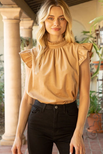 A model wearing a tan top and black jeans, showcasing the Lucy Ruffle Sleeve Top with trendy ruffle sleeves and cute tie back detailing in soft corduroy material.