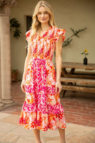 Our Frankie Floral Midi Dress is a must-have for any garden party! This smocked dress features a vibrant pink and orange floral pattern for a stylish look.