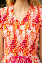 Load image into Gallery viewer, A model wearing a pink and orange floral dress, perfect for a garden party. Stay stylish and comfortable all day in our Frankie Floral Midi Dress!
