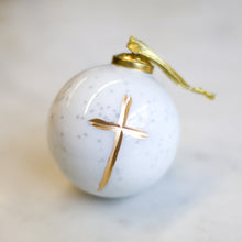 Load image into Gallery viewer, A beautiful frosted glass ornament with a white background and a gold cross in the center. It has a gold ribbon for hanging.
