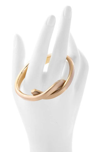 A woman's hand delicately holds a gold ring on a mannequin, showcasing a Knotted Cuff Gold Infinity Bracelet Hinged cuff.