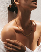 Load image into Gallery viewer, An elegant woman donning a white shirt and a versatile gold necklace. This timeless figaro chain measures 44 cm and includes an 8 cm extension chain.
