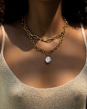Load image into Gallery viewer, Enhance your style effortlessly with this pearl and gold chain necklace. Featuring a genuine freshwater pearl on a chunky gold chain, this necklace adds a touch of elegance to any outfit. The T bar closure and unique shape of the pearl make it a fashion-forward choice. Chain length: 45 cm.
