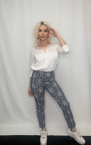 A stylish woman exudes elegance in a pristine white shirt and chic blue pants, showcasing the GripeLess Pull On Pant Sultan's Dining Room-Gretchen Scott collection.