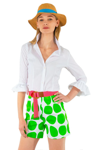 A  woman wearing a white Priss Blouse with green polka dot shorts by Gretchen Scott.